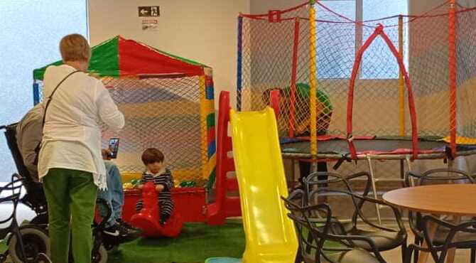 Kit kids da JD Kids montado em salão com piscina de bolinhas, cama elástica com rede colorida, escorrega amarelo e gangorra vermelha